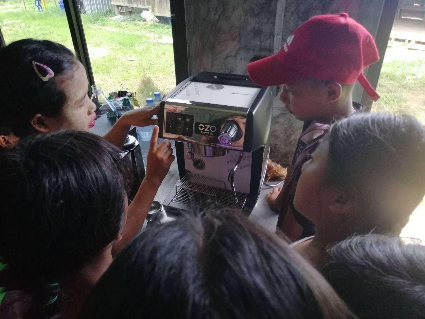 The youngsters are practicing how to use the coffee maker, gaining hands-on experience to develop their vocational skills and confidence.