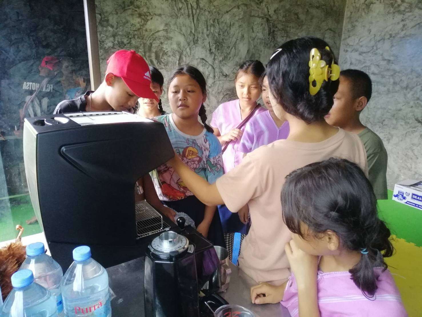 Youngsters practice using the coffee maker, gaining practical skills to build their future and contribute to their community’s growth.
