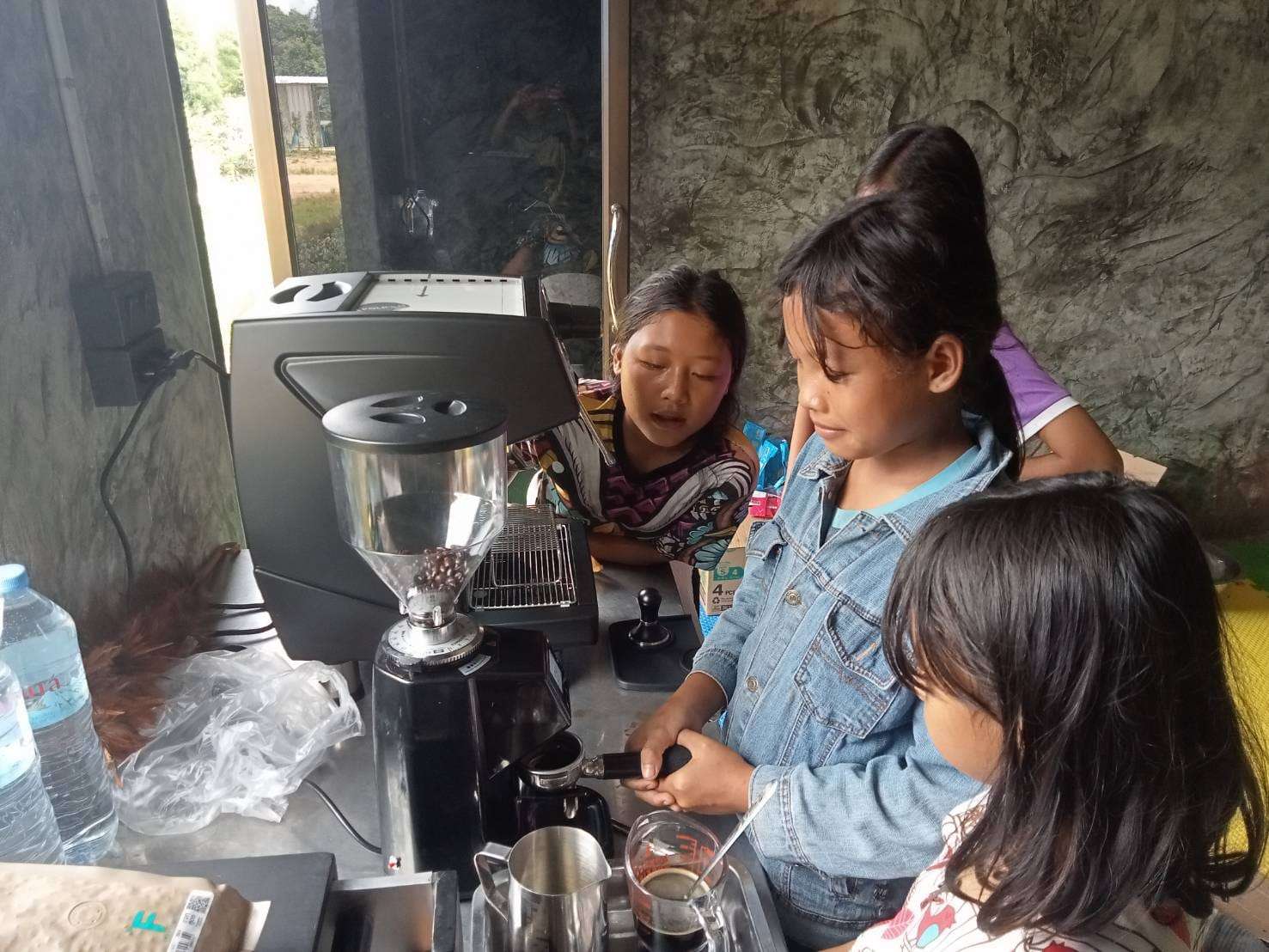 Youngsters are practicing how to use the coffee maker, developing essential skills to serve customers and build their future careers.