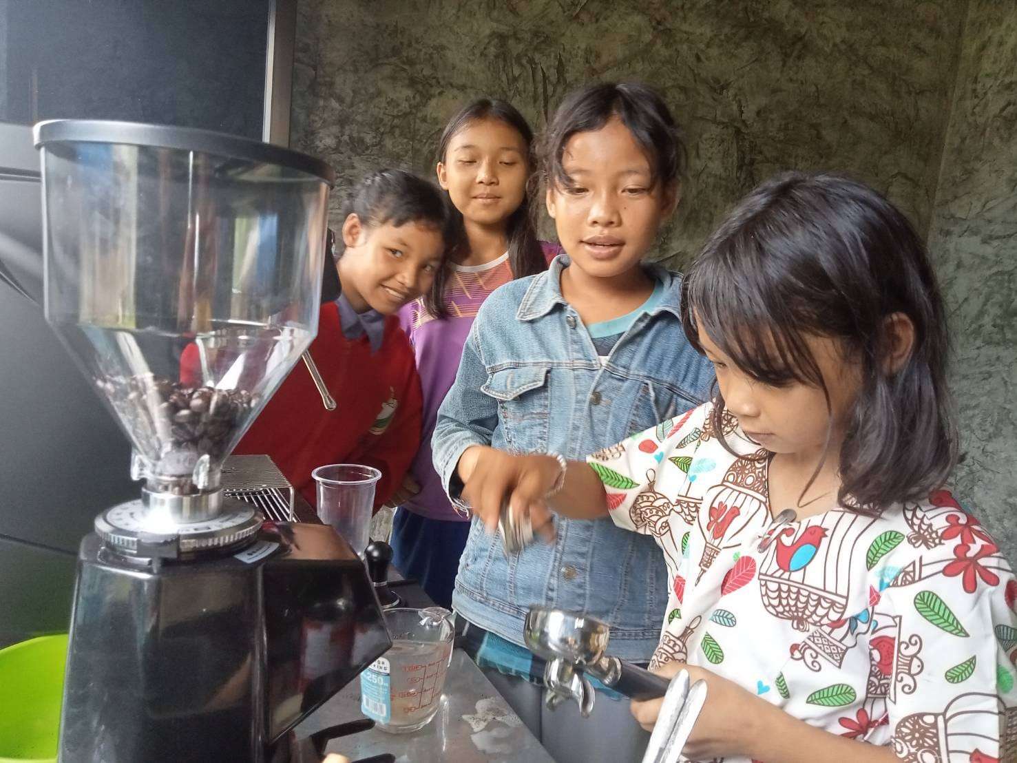 The youngsters are practicing how to use the coffee maker, gaining hands-on experience to enhance their vocational skills 